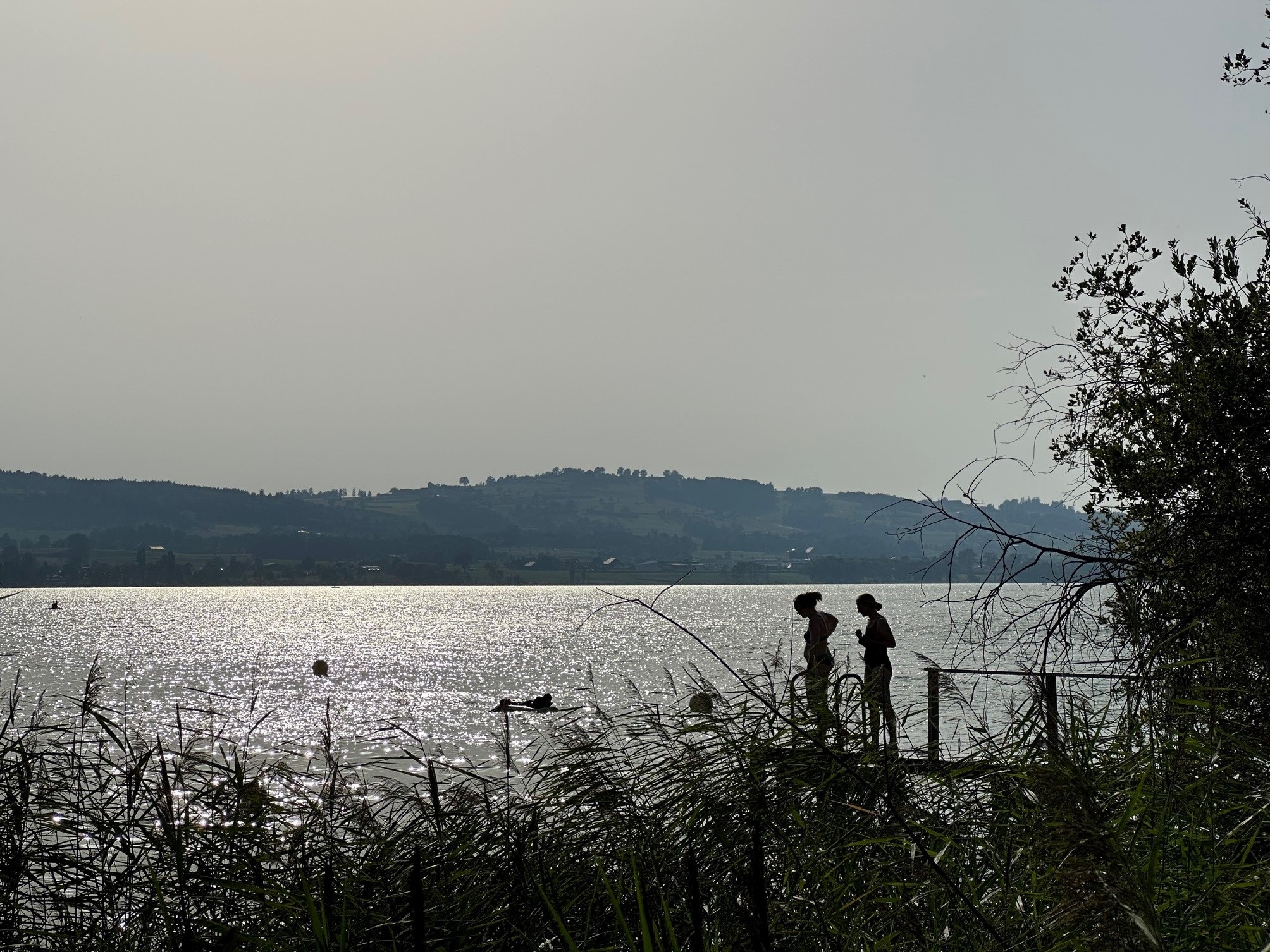 Silhouettes of two women on a jetty at a lake Sempach